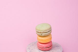 Three different color macarons on a marble plate.