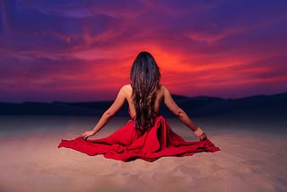 Woman meditating on a beach in a sunset