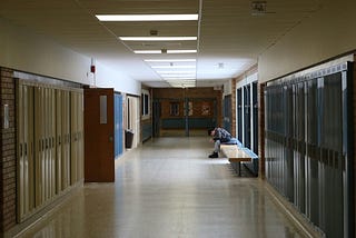 A bullied child is sitting alone on a bench at school.