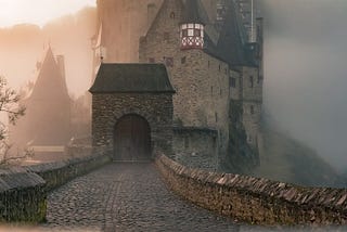[image description: a castle in the dawn fog after a rain.]