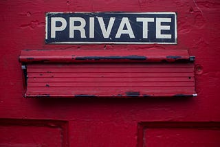 A close-up of a mail slot on a red door with the word Private above it.