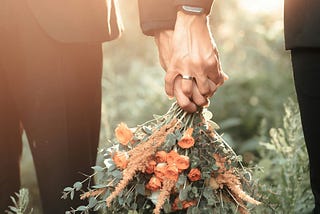 Two hands holding a bouquet of flowers.