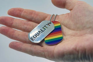 Hand holding a rainbow and equality keychain