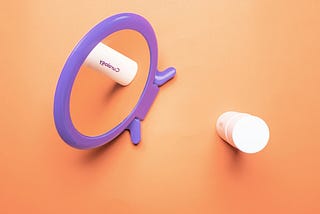 A vibrant purple mirror and skincare products are arranged against a warm orange background.