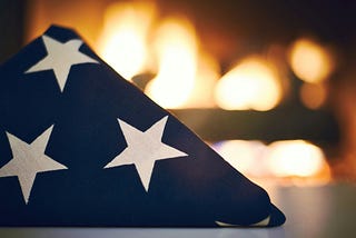 A folded flag laid before rows of flames.