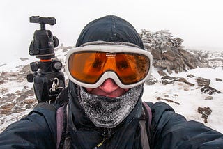 A man in ski goggles with a frozen balaclava.