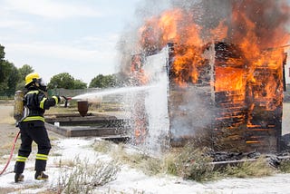 A firefighter using a hose to extinguish a fire