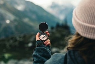 woman in the mountains looking at a compass