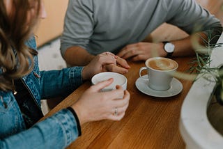 Couple holding hands and drinking coffee