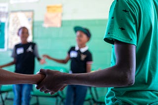 children in a classroom holding each other’s hands