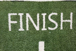 The word finish in white painted on a green lawn