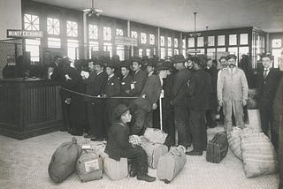 Antique photo of men grouped with baggage, one boy seated on suitcase in front