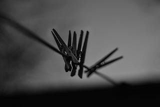 Black and white photo of clothe line with 4 clothes pins on them.
