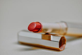 A red lipstick is open and resting on its gold cover