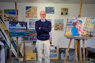 An artist stands proudly by his paintings, demonstrating the link between creativity and confidence.