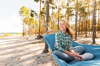Young woman sitting in hammock and looking away