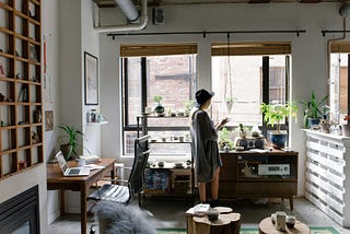 A woman in an apartment full of plants.