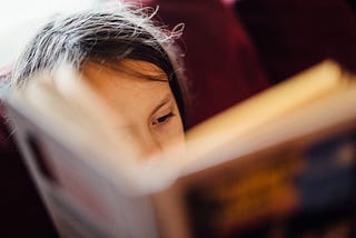 A person partially hidden by the book they’re reading