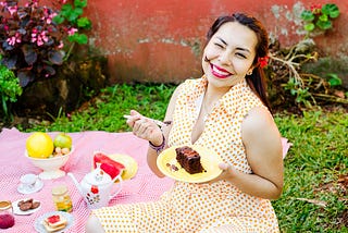 Image of a lady eating Chocolate cake smeared on her face, but she is happy and content