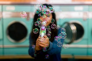 Woman blowing soap bubbles in front of washing machines