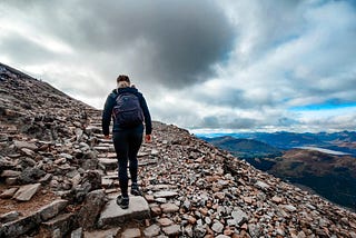 Person at the bottom of a set of stone steps, leading up a mountain