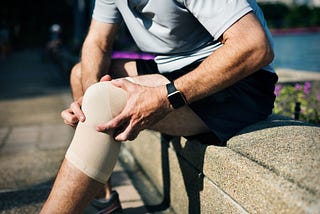 Image of a man holding his knee in pain.