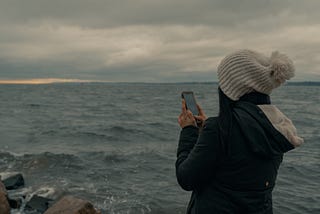 Photo of someone texting by the ocean