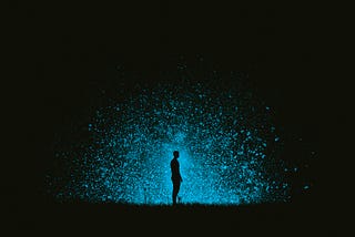Dark silhouette of a person against a cosmic blue light and black background.