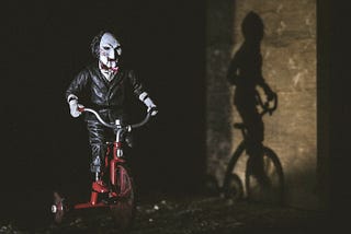 Billy puppet from the Saw movies riding on a tricycle.