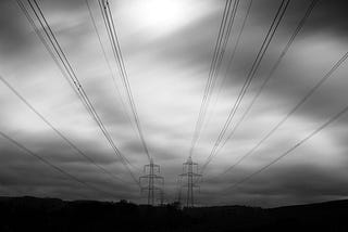 Two sets of power lines against a gray sky.