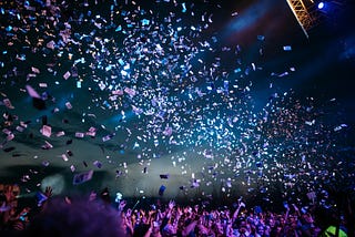 Bright blue and pink confetti tossed into a dark blue sky.