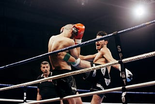 A fighter landing a roundhouse kick against their opponent’s body.