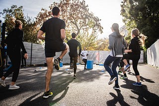 A group of people is exercising at outdoor surrounded with colorful trees in arousing, sunny weather!