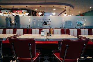 an empty booth at an old-school diner with condiments and a napkin dispenser