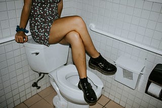 Lady sitting on toilet tank