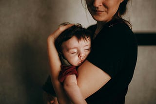 Mother holding her blissfully sleeping child.