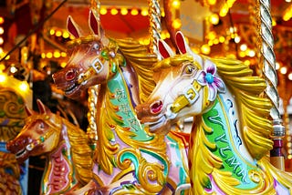 Closeup of three brightly colored horses on a lighted carousel.