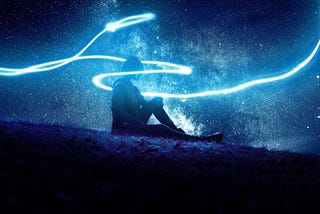 Person sitting on a hillside with a stream of light around them.