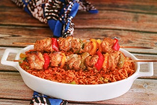 A plate of Jollof rice and skewed chicken.