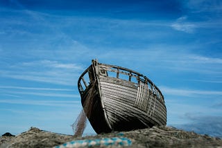A boat on a rocky ledge which has run ashore
