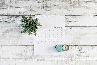 January calendar on a wooden background with plant and clock.