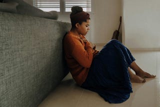 Girl sitting, back against couch, holding both hands over her heart