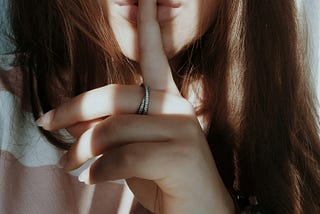 A woman makes the hand gesture to keep quiet
