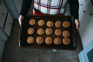 A woman with a baking sheet full of homemade cookies