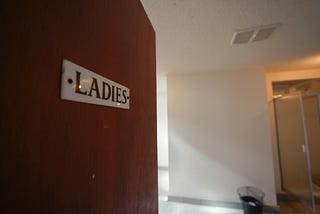 Door opening to reveal a public washroom, marked “LADIES.”