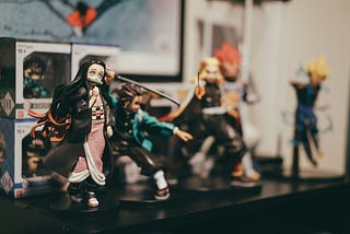 Action figures representing characters from the popular anime series Demon Slayer are arranged on a shelf in what appears to be someone’s bedroom.