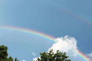 A rainbow with a blue sky in the background.