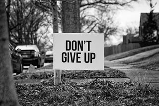 A sign with “Don’t Give Up” in bold on the front.