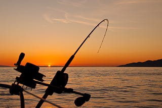 Boat-fishing rod under tension at dawn