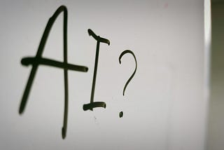 AI? written in black marker pen on a whiteboard.